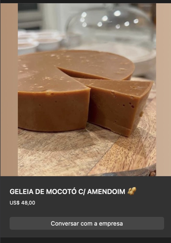Bloco de geleia de mocotó com amendoim, cor caramelo escura, formato circular cortado em pedaços sobre tábua de madeira. Textura firme.