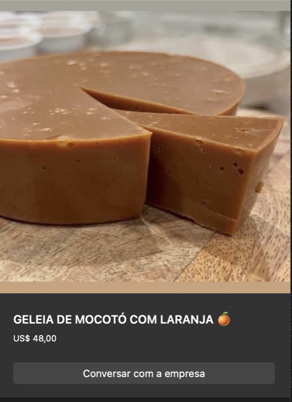 Geleia de mocotó com laranja em formato de disco firme cor marrom-âmbar, cortada em pedaços, sobre tábua de madeira clara. Textura densa e brilhante.