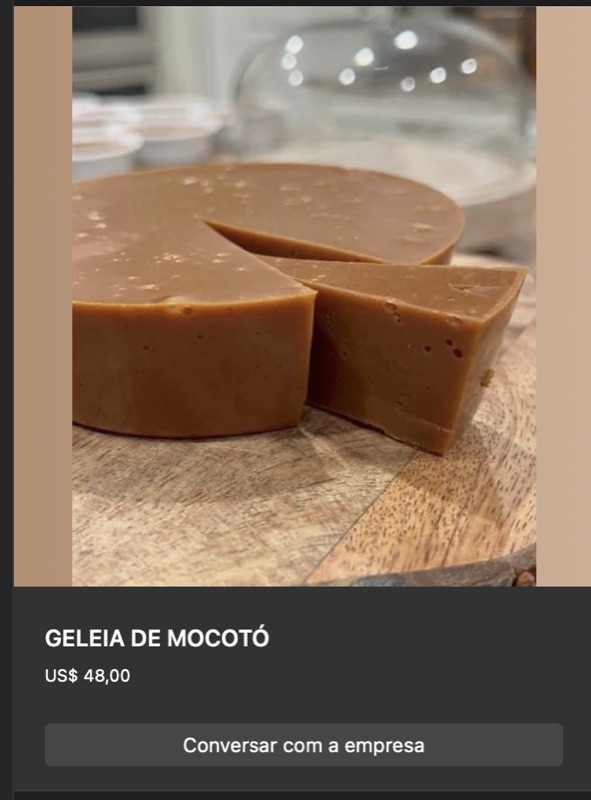 Bloco arredondado de geleia de mocotó firme em tom marrom-claro caramelo, partido ao meio, exposto sobre tábua de madeira. Textura densa de gelatina natural.