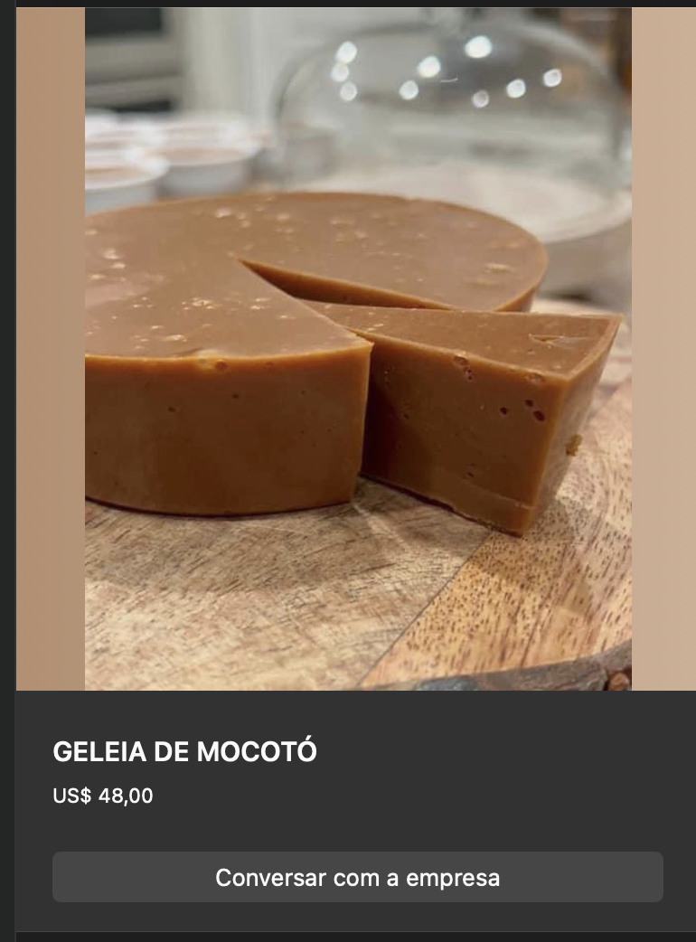 Bloco arredondado de geleia de mocotó firme em tom marrom-claro caramelo, partido ao meio, exposto sobre tábua de madeira. Textura densa de gelatina natural.