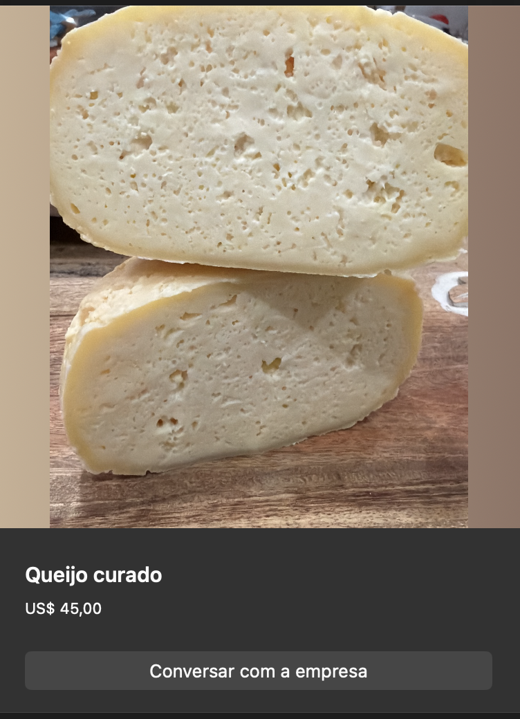 Queijo curado em formato arredondado, cor amarelo-creme pálido, partido ao meio mostrando textura interna firme com pequenos olhos. Sobre tábua de madeira.
