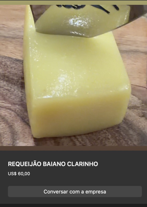 Bloco de requeijão baiano clarinho em cor amarelo-pálido bem clara, formato cúbico, superfície lisa brilhante. Sobre tábua de madeira clara, ao lado de outro queijo.