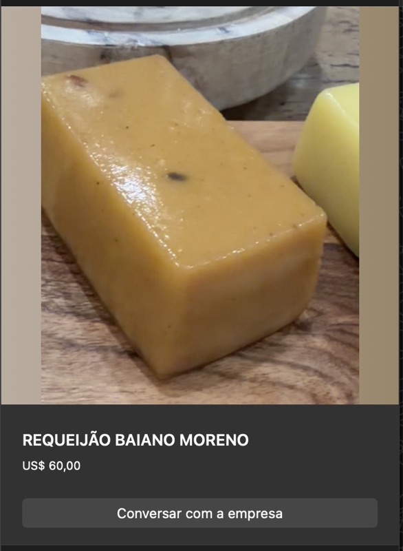 Bloco retangular de requeijão baiano moreno em cor dourada-caramelo intensa, com pequenos pontos escuros caramelizados. Sobre tábua escura com limão amarelo ao lado.